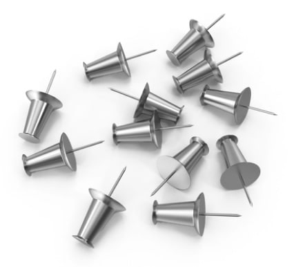 A bunch of silver push pins scattered on a table